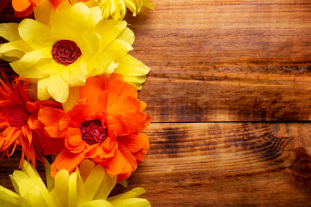Paper flowers on wooden table background. Decoration floral pattern, springtime, Easter, Birthday, Happy Womens Day, Mothers Day. Copy space for your message. Table top view.の写真素材