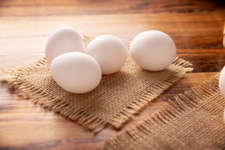 Many white chicken eggs on rustic wooden table. Very popular nutritious and economic food product. Closeup image.の写真素材