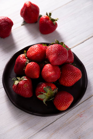 Fresh organic strawberries (fragaria) on wooden table. Also known as Frutilla in some Spanish-speaking countries, it is a forest fruit that is eaten alone or as an ingredient in multiple recipes.の写真素材