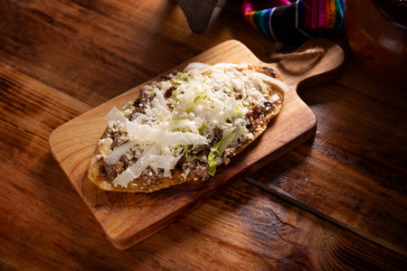 Huarache (food). Typical Mexican oval-shaped dish, made with corn dough and beans, commonly covered with lettuce, cheese, sauce and some protein such as steak, rib or egg.の写真素材