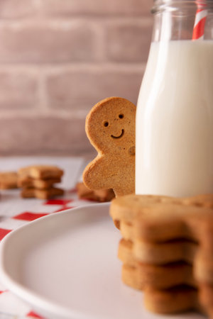 Homemade smiling gingerbread man cookie peeking out from behind a milk glass jar. These cookies are traditionally made in the holiday season for Christmas.の写真素材