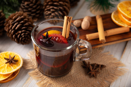 Spiced wine or Christmas mulled wine with orange, cinnamon, star anise, clove, nutmeg and other ingredients on a wooden rustic table. Traditional hot drink at winter time and Christmas holidays.の写真素材