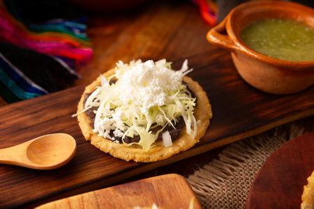 Sope. Traditional homemade Mexican food prepared with flattened and pinched on the border fried corn dough covered with refried beans, green or red sauce, lettuce, cheese and creamの写真素材