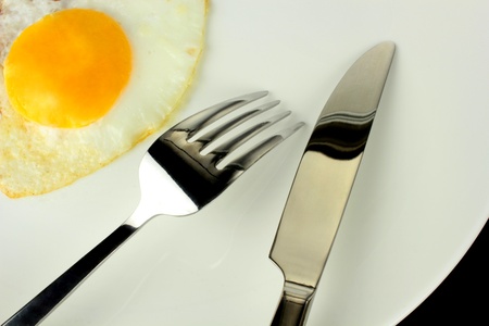 Fried egg with  fork and knife on a plate の写真素材