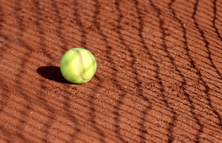 Tennis ball on a tennis clay court with net shadowの写真素材