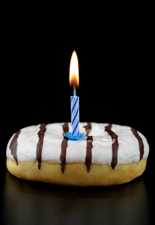 Doughnut with birthday candle on black background の写真素材