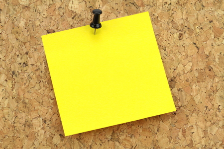 Yellow note paper on cork board  Macro image の写真素材
