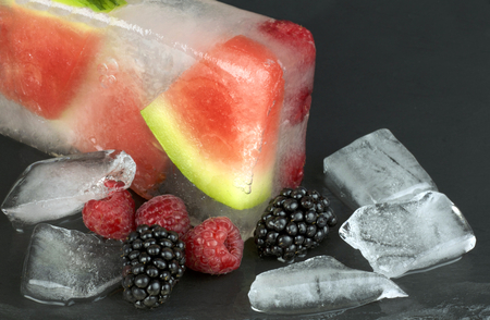 Frozen watermelon slices and berries on black backgroundの写真素材