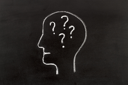 Hand drawing human head shape with chalk  on blackboard and question marksの写真素材