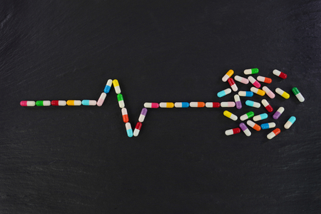 ECG graph with Colorful medical capsules on black background. Conceptual image.の写真素材
