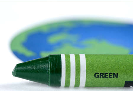 Green crayon in front of a drawing of the earth.の写真素材