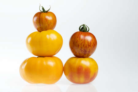 Heirloom tomatoes stacked like red and yellow snowmen.の写真素材