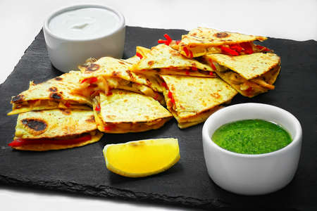 Quesadilla sliced with vegetables and sauces on the table. horizontal view from above