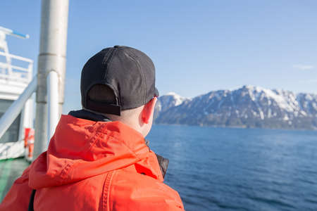 man in a cap on the shore of the ship. He is looking into the distance. Beautiful landscape