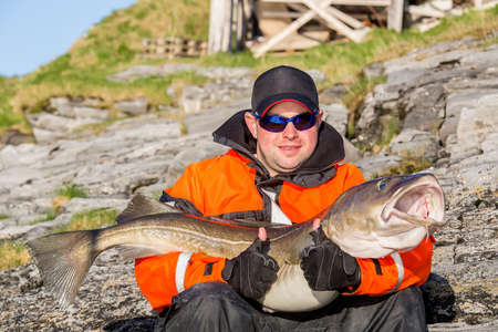 Fisherman in glasses holding big fish on his hands. Smiling