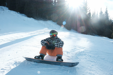 snowboarder with a fastened board sits on the snow,