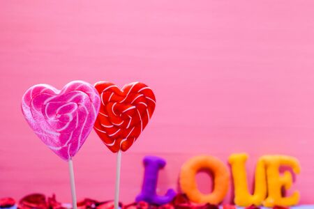 Two heart shaped lollipops. inscription love in multicolored letters from felt material. Red hearts...