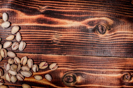 a handful of Pistachio nuts are scattered on a wooden table. place for the descriptionの写真素材