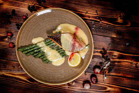 A top-down shot of a salmon steak with asparagus and lemon sauce, plated on a wooden table. Perfect for gourmet food marketing, restaurant promotions, and upscale culinary content.の写真素材