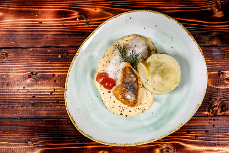 Overhead view of a balanced and appetizing dish: pan-fried fish fillet with mashed potatoes, creamy...