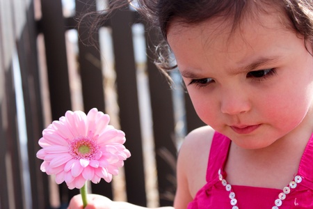 Adorable child holding a pink flowerの写真素材