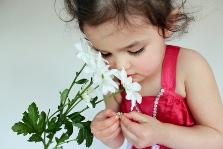 Adorable little girl smelling white flowersの写真素材