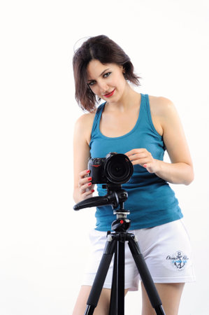 Young beautiful brunette woman with camera on tripod isolated on white backgroundの写真素材