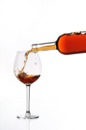 Pouring red wine into a glass, isolated on a white background