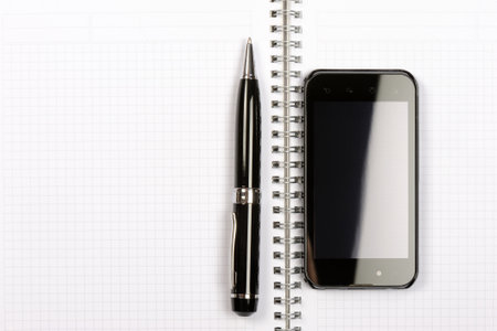 Smartphone with notebook and pen isolated on white background. Top viewの写真素材