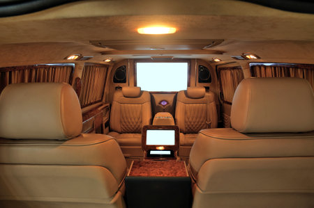 Interior of a luxury car with leather seats and a TV.