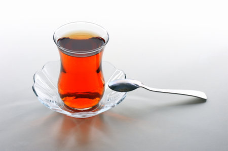 Turkish tea in a glass cup with a spoon on a white backgroundの写真素材