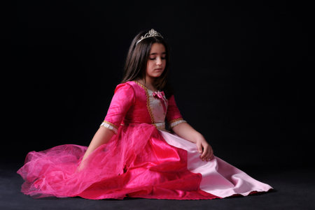 Portrait of a beautiful girl in a pink dress on black backgroundの写真素材
