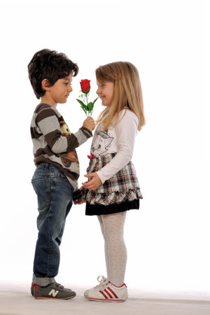 Little boy giving a red rose to his little girlfriend, isolated on white backgroundの写真素材