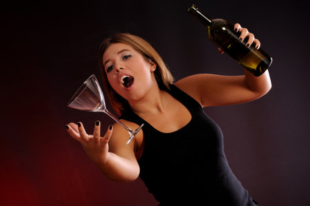 Young woman with a bottle of wine and a glass on a dark background levitationの写真素材