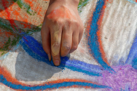 An artist hand at work making beautiful works of art on the street using soft pastel chalk while attending the Madonnari festivalの写真素材