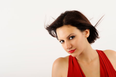 Portrait of a beautiful young woman with red dress on white backgroundの写真素材