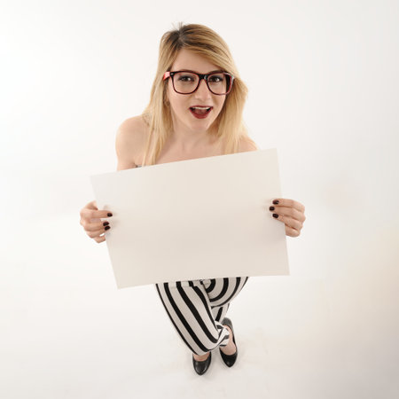 beautiful girl with blonde hair and glasses holding white blank banner with text space on white backgroundの写真素材