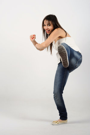 Young woman dancing breakdance in the studio on white background. in a kicking position with one foot up in the airの写真素材