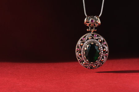 Jewelry pendant with precious stones on a red and black background.の写真素材