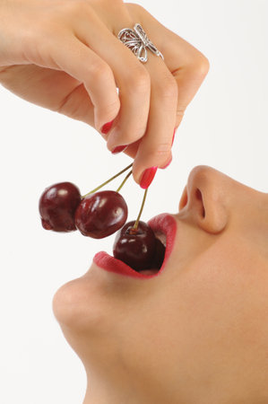 Cherries on the lips of a young beautiful woman on a white backgroundの写真素材