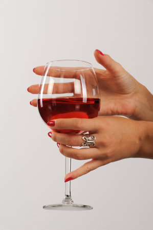 Woman's hands with red manicure holding a glass of red wineの写真素材