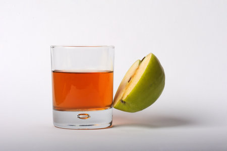 A glass of apple juice and an apple on a white background.の写真素材
