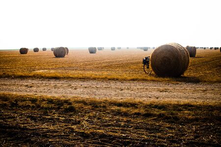 Touring bike hidden by a hay ball in a big orangee-colored fieldの写真素材