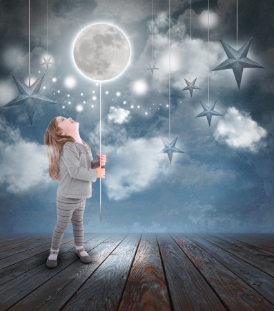 Young little girl playing at night with a balloon moon on a string with stars in the blue sky with clouds for a dream concept. Young little girl playing at night with a balloon moon on a string with stars in the blue sky with clouds for a dream concept.