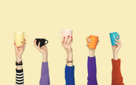 Many different arms raised up holding coffee cupの写真素材