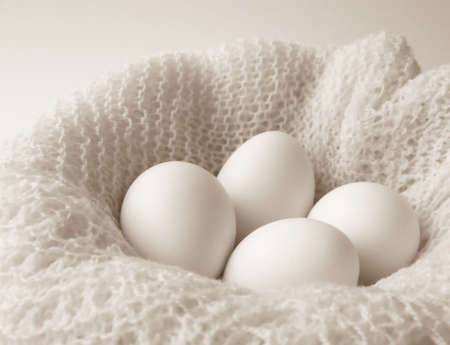 Image of four white eggs sitting in a bowl covered with a finely crocheted shawl.  Black and white with horizontal orientation.の写真素材