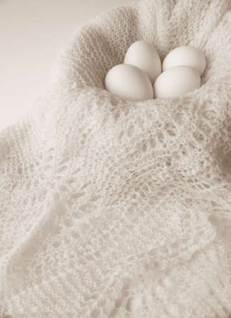 Image of four white eggs sitting in a bowl covered with a finely crocheted shawl.  Black and white with vertical orientation.の写真素材
