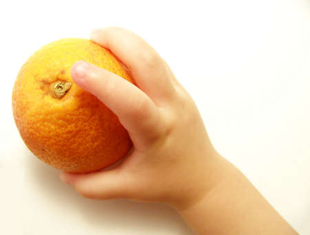 Image of a bright blood orange being held by a small child's hand.の写真素材