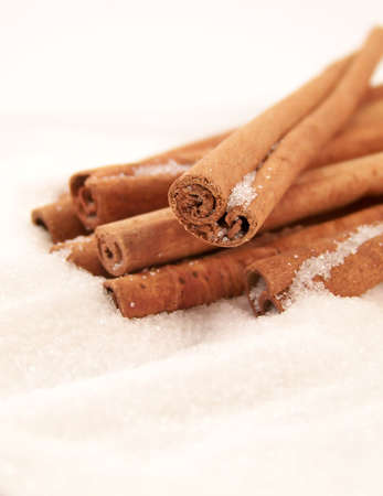 Vertical image of cinnamon sticks piled in white granulated sugar, viewed at an angle.の写真素材