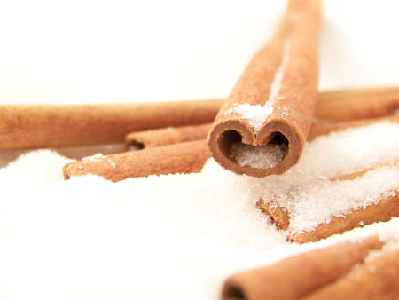 Horizontal image of a heart-shaped cinnamon stick in white granulated sugar, with other sticks visible.の写真素材